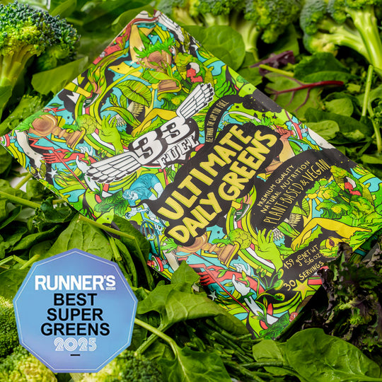 Colorful  33fuel Greens powder package of 'Ultimate Daily Greens' surrounded by fresh green vegetables with a 'Runner's Best Super Greens 2025' badge.